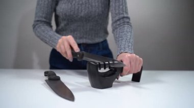 Bir kız bileyiciyle bıçağı keskinleştirir.