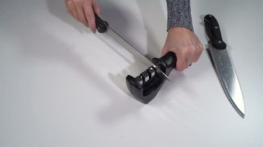Bir kız bileyiciyle bıçağı keskinleştirir.