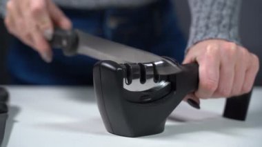 Bir kız bileyiciyle bıçağı keskinleştirir.