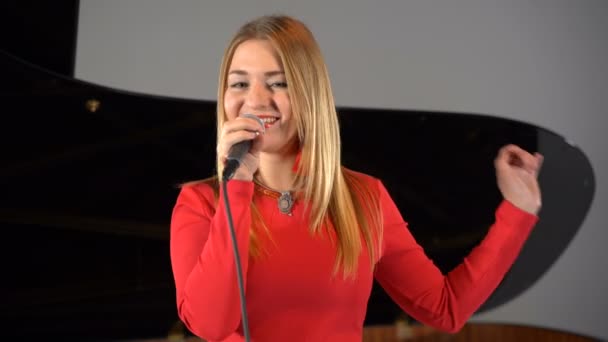 Una chica canta en un micrófono en el escenario — Vídeos de Stock