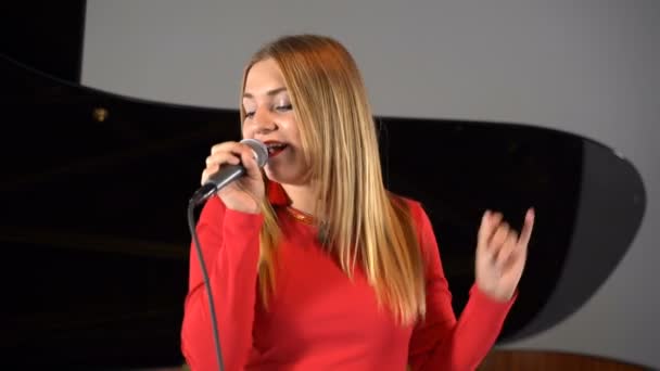 Una chica canta en un micrófono en el escenario — Vídeos de Stock