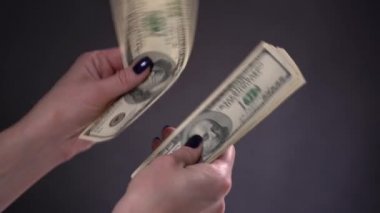 Kız siyah arka planda dolar banknotlarını dikkate alıyor.