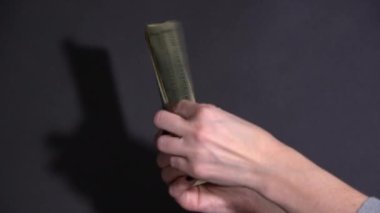 Kız siyah arka planda dolar banknotlarını dikkate alıyor.