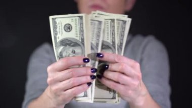 Kız siyah arka planda dolar banknotlarını dikkate alıyor.