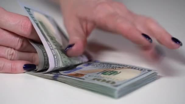 Das Mädchen betrachtet eine Packung Dollarscheine auf einem weißen Tisch — Stockvideo
