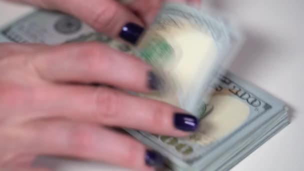 La fille considère un paquet de billets de dollar sur une table blanche — Video