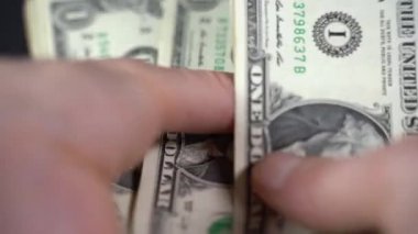 Adam siyah arkaplanda dolar sayıyor.