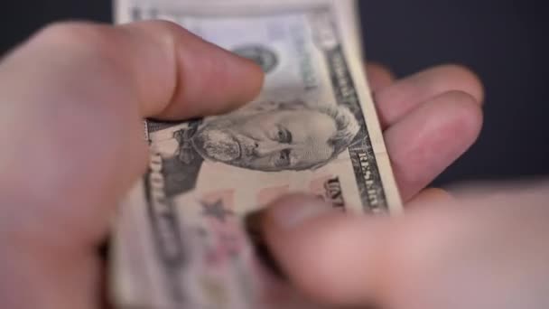 Человек пересчитывает долларовые купюры на черном фоне — стоковое видео