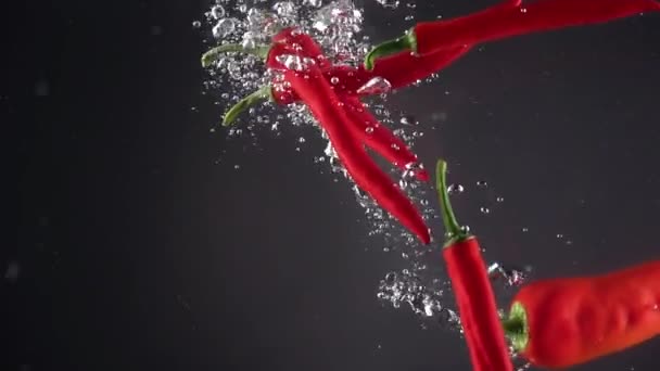 Pimientos picantes cayendo al agua. Movimiento lento — Vídeos de Stock