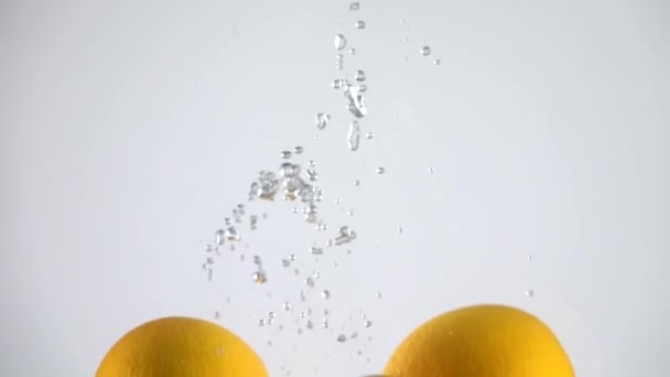 Naranjas cayendo al agua. Movimiento lento — Vídeos de Stock