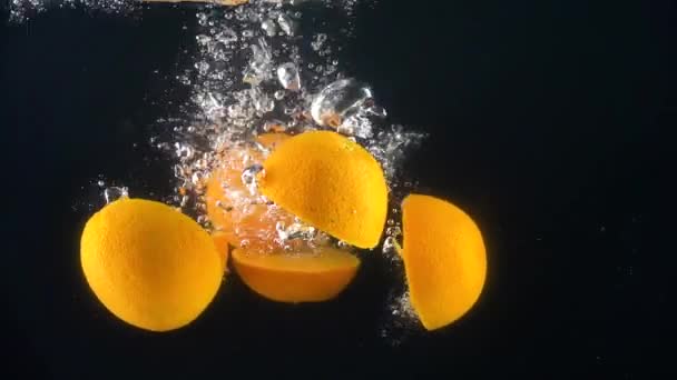 Naranjas cayendo al agua. Movimiento lento — Vídeos de Stock