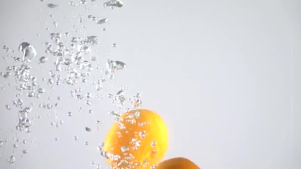 Tangerines tombant dans l'eau. Mouvement lent 