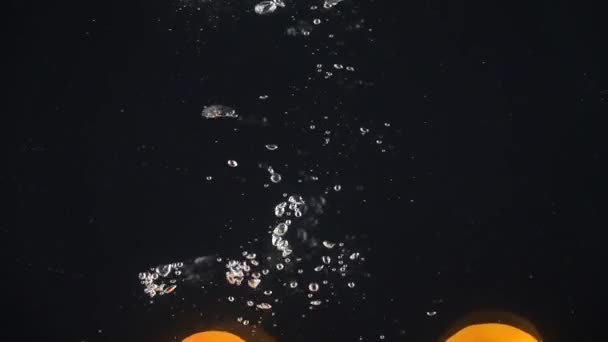 Tangerines falling into the water. Slow motion — Stock Video