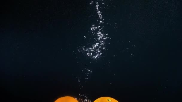 Mandarinen fallen ins Wasser. Zeitlupe — Stockvideo