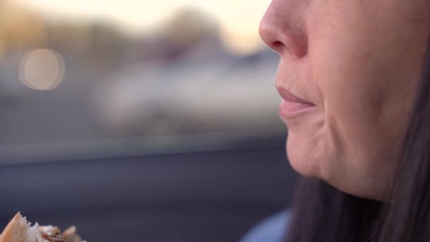 Ragazza mangia un cheeseburger in una macchina — Video Stock