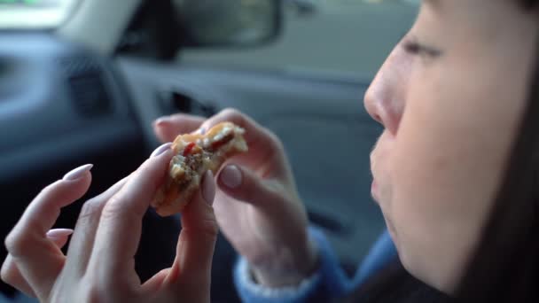 La chica come una hamburguesa con queso en un coche. Movimiento lento — Vídeo de stock