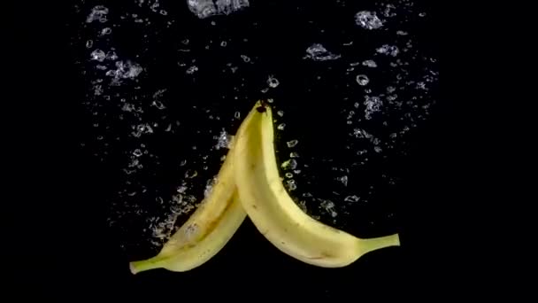 Бананы падают в воду. Медленное движение 250fps — стоковое видео