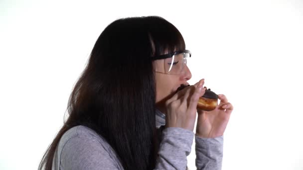 Mujer con máscara médica y gafas come un donut — Vídeo de stock