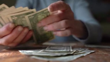 Yaşlı kadın dolarları sayıyor.