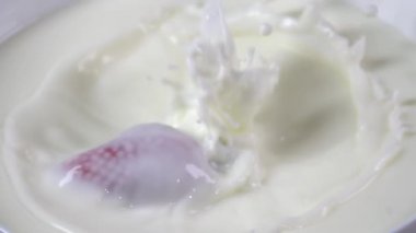 Çilekler süte dökülüyor. Yavaş çekim 500fps