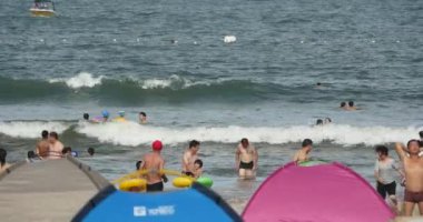 Qingdao Çin-Temmuz 12, k 2017:4 birçok kişi kalabalık kumlu plajda insanlar denizde Yüzme.