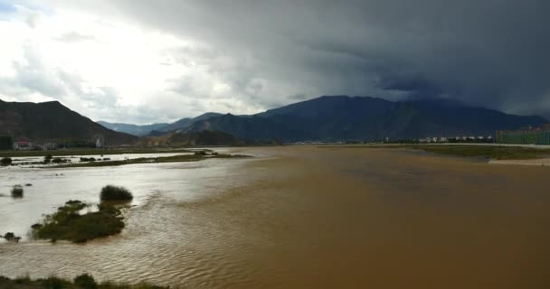 4k rio Lhasa, longe nuvens escuras massa rolando sobre o Tibete montanha . — Vídeo de Stock