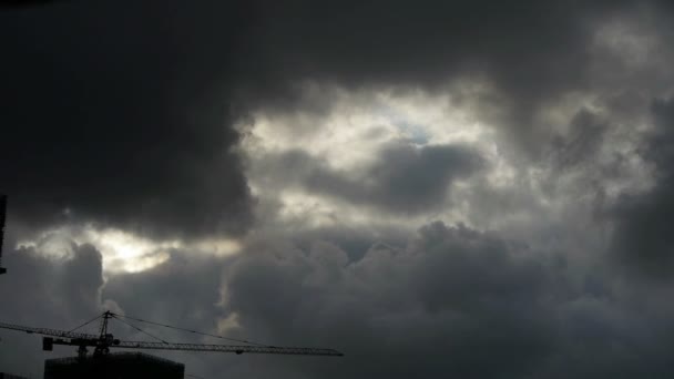 Nuvens escuras cobrem céu, guindastes, edifício alto, silhueta da casa. — Vídeo de Stock