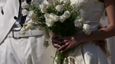 Damat ve gelin birlikte, bir buket çiçek taşıyan gelin.