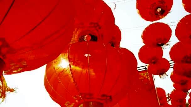 Φούντα κόκκινα φανάρια που λικνίζονται στον άνεμο, πίσω από τον ήλιο, στοιχεία της Ανατολής, Κίνα το νέο έτος. — Αρχείο Βίντεο