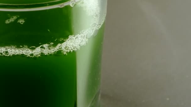 Espuma y ampolla en la superficie del agua.Una taza de mosto verde, jugo de trigo, blis — Vídeo de stock