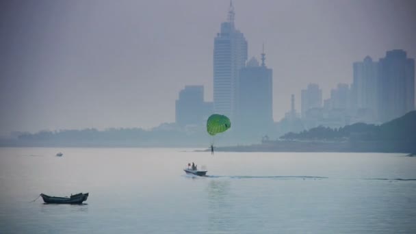 Clipper boat dragging paragliding,horizon is high-rise buildings. — Stock Video