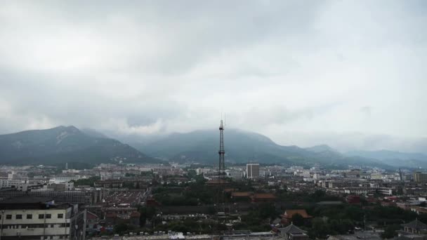 Nubes en la cima de la colina, edificios de la ciudad que dependen de la montaña.Panorámica de Taishan, T — Vídeo de stock