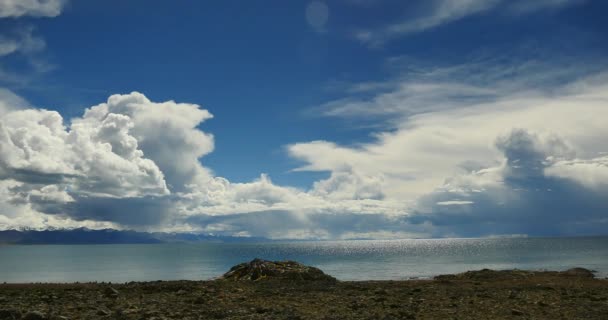 4k enorme massa nuvole rotolando sopra il lago namtso & montagna di neve, pregare bandiera nel vento . — Video Stock