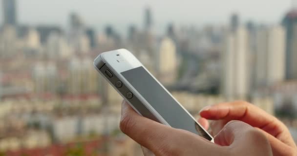 4k menselijke met behulp van een smartphone tegen de achtergrond van de moderne stedelijke gebouw. — Stockvideo