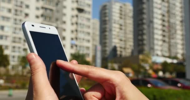 4k eine Frau mit einem Smartphone Aganisten Business Building Hintergrund. — Stockvideo