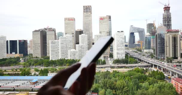 China-Sep 09,2017: 4k, humano usando un teléfono inteligente con edificio de negocios y el tráfico urbano de fondo . — Vídeo de stock