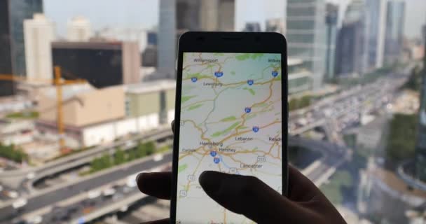 4k, बिजनेस बिल्डिंग और शहरी यातायात बैकग्राम के साथ स्मार्टफ़ोन पर मानव ब्राउज़ नक्शा — स्टॉक वीडियो