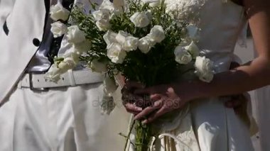 Damat ve gelin birlikte, bir buket çiçek taşıyan gelin.