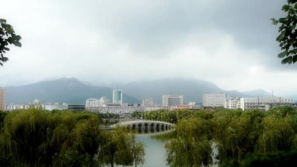 Chine-08 août 2016 : Pont en arc sur le lac dans le parc des saules.La ville compte sur des collines lointaines . — Video