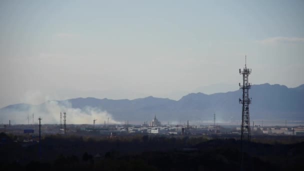 Panoráma a város & gyári füst támaszkodva hegyek, torony a hegyen. — Stock videók