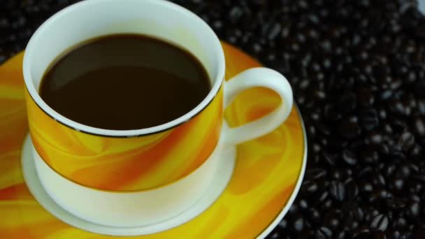 Girando una taza de café y granos de café de fondo, vista superior . — Vídeos de Stock