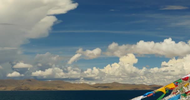 4 k τεράστια σύννεφα μάζα τροχαίο πάνω από τη λίμνη namtso & χιόνι στο βουνό, προσεύχονται σημαία στον άνεμο. — Αρχείο Βίντεο