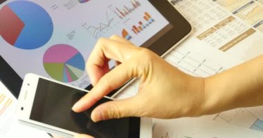 4 k iş adamları smartphone ve ipad üzerinde mali veri tarama.