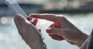 Deniz kenarında, köpüklü su yüzeyi bir akıllı telefon kullanan 4 k A kız.