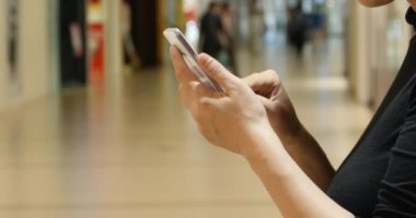 Alışveriş Merkezi ve süpermarket kapalı arka plan karşı bir akıllı telefon kullanan 4 k A kadın.