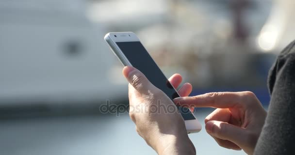 4k Uma menina usando um smartphone à beira-mar, iate e vela no porto . — Vídeo de Stock