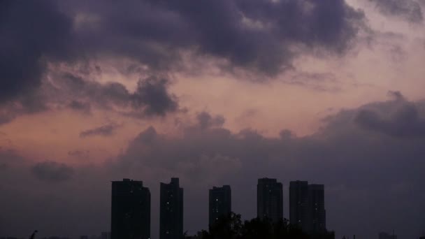 Nuvens escuras cobrem o céu à noite, construindo arranha-céus, silhueta da casa . — Vídeo de Stock