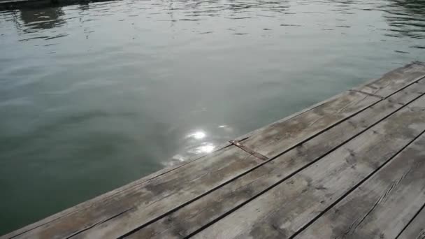 Panorámica de Ondas olas en el lago y muelles de madera, reflejo de la luz del sol en el agua . — Vídeo de stock