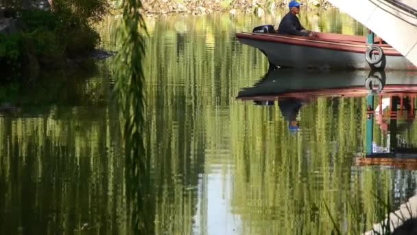 China-Oct 08,2017: ancianos en barco bajo puente, reflejo de sauce en el lago, olas de agua en movimiento . — Vídeo de stock