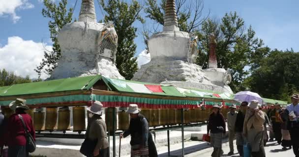 4k tibet people turn spinning buddhist prayer wheel, Potala & white stupa. — 图库视频影像